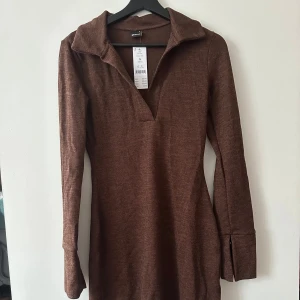 Brun ribbad klänning från Gina Tricot - Säljer en snygg brun ribbad klänning från Gina Tricot. Klänningen har långa ärmar och en stilren krage. Perfekt för en chic och avslappnad look. Passar bra till både vardag och speciella tillfällen.
