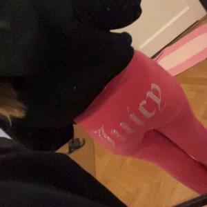 Rosa velour byxor Juicy Couture - Säljer ett par riktigt iögonfallande Juicy Couture-byxor i skrikrosa! På baksidan glittrar texten ‘Juicy’ i stenar – ett måste för dig som älskar den klassiska Y2K-stilen med extra bling.  Nypris ca 1200 kr, men de är knappt använda och i toppskick.  Hör av dig om du vill ha fler bilder eller info!