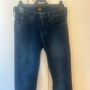 Mörkblå jeans från Lee (Scarlet) W27 L31 - Snygga mörkblå jeans från Lee med klassisk femficksdesign och knappgylf. Perfekta för en avslappnad stil. De har en smal/skinny passform som ger en modern look.