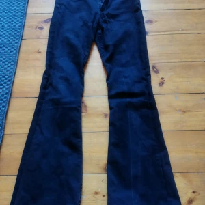 Svarta byxor med bootcut - Snygga svarta högmidjade byxor i bootcut-stil. Perfekta för en trendig look med sin vida passform nedtill. Byxorna har en klassisk design med fickor bak och är tillverkade i ett bekvämt material. 