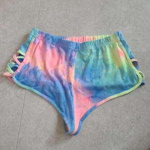 Färgglada shorts med knytband - Säljer ett par färgglada shorts från CBR med ett coolt tie-dye mönster i blått, rosa och gult. Shortsen har knytband på sidorna som ger en unik look.
