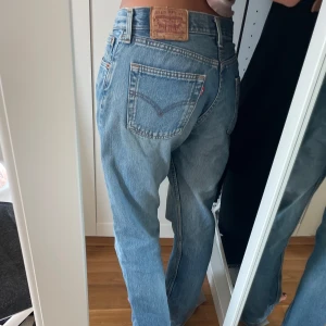 Levis jeans i ljusblå denim - Säljer ett par klassiska Levis jeans i ljusblå denim. De har en hög midja och en straight passform. Perfekta för en avslappnad stil. Jeansens ikoniska bakfickor och knappgylf ger en tidlös look.