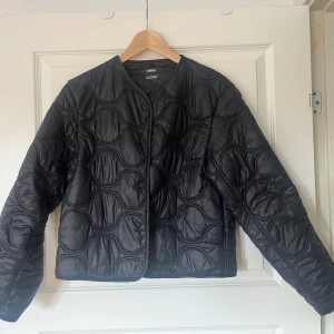Svart quiltad jacka från Mango - Säljer en svart quiltad jacka från MNG. Jackan har en rund halsringning och långa ärmar. Perfekt för en stilren look.