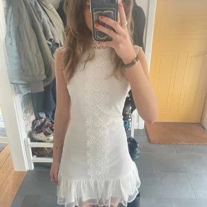 Vit ärmlös klänning med spetsdetaljer-studentklänning  - Säljer en söt vit klänning med spetsdetaljer framtill och volangkant nedtill. Klänningen är ärmlös och passar perfekt som studentklänning! Säljer då jag hittat en annan själv. Storlek s men passar xs också beroende på hur man vill att den ska sitta! 