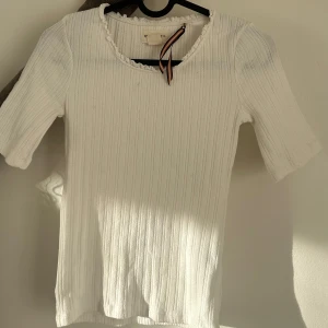 Vit ribbad topp från Holly & Whyte - Säljer en jättefin vit topp som inte kommer till användning tyvärr! Toppen har en söt volangdetalj vid halsen och är i storlek xs! Hör av dig om du har ytterligare frågor❤️❤️