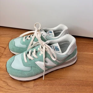 Mintgröna sneakers från New Balance - Snygga mintgröna sneakers från New Balance med vit sula och snörning. Skorna har en klassisk design med mockadetaljer och är perfekta för en avslappnad stil. (OBS! Små i storleken)