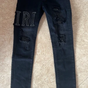  Amiri jeans - Snygga svarta jeans från Amiri med slitningar och broderade bokstäver. Perfekta för en trendig look. Jeansen har en tight passform och är tillverkade i ett slitstarkt material.
