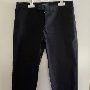 Svarta kostymbyxor - Snygga svarta kostymbyxor med en klassisk design. Byxorna har en rak passform och är perfekta för en stilren look. De har hällor för bälte och en diskret dragkedja framtill.