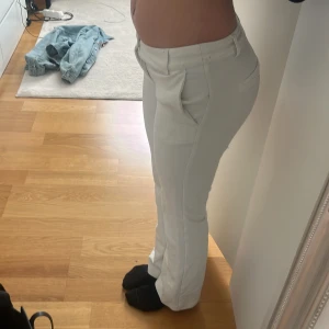 Vita kostymbyxor - Snygga vita kostymbyxor med låg midja och rak passform. Byxorna har en klassisk design med fickor och knäppning fram. Perfekta för en stilren look. Ny pris 500kr. Byxorna är ganska noppriga därför säljer jag billigare.