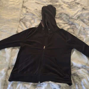 Svart hoodie med dragkedja - Säljer en stilren svart hoodie med dragkedja och huva. Den har långa ärmar och praktiska fickor framtill. Perfekt för en avslappnad look. 