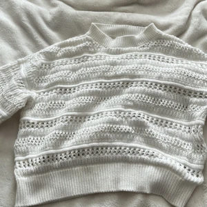 Vit stickad tröja - Säljer en vit stickad tröja med ett snyggt hålmönster. Tröjan har långa ärmar och en ribbad kant vid halsen och ärmsluten. Perfekt enkel fast snygg look💕