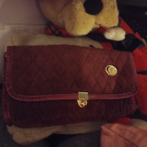 Quiltad röd axelväska - Snygg quiltad röd axelväska med guldfärgad låsdetalj. Perfekt för att bära dina nödvändigheter med stil. Väskan har en elegant design och är lätt att matcha med olika outfits.