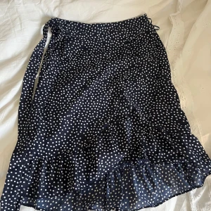 Prickig sommarkjol - Kjolen är i superskick! Den är knappt använd och har inga skador. Kjolen har en volang som man ser på bild 2, och den har ett band man kan knyta runt midjan.