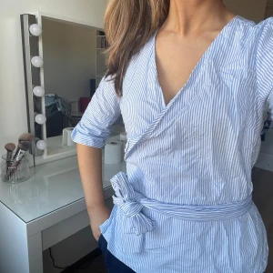 Blå vit randig omlott blus - En kortärmad blå vit randig omlott blus som är ej använd. Säljer då jag som sagt aldrig använt den.