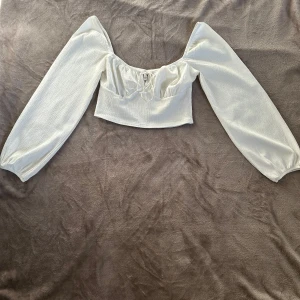 Vit blus från NLY Trend - Säljer en söt vit blus från NLY Trend med långa puffärmar och knytning framtill. Blusen är croppad och har en lätt ribbad struktur som ger en fin textur. Perfekt för en stilren look!      Storlek S                                                           Använd fåtal gånger, inga defekter eller synliga tecken på slitage                                                    Om ni har frågor är det bara att höra av sig och priset går alltid att diskutera🙌🏻💞