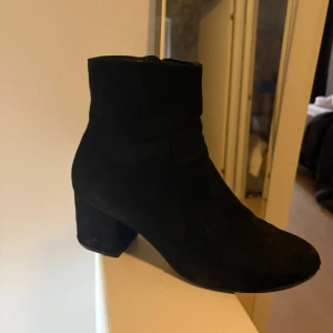 Svarta mocka boots med klack - Snygga svarta boots i mocka med en bekväm klack och dragkedja på sidan. Perfekta för både höst och vinter. Stilren design som passar till många olika outfits.