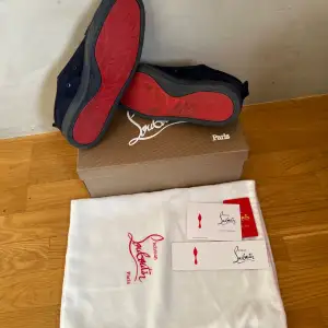 Snygga marinblå sneakers i mocka från Christian Louboutin med den ikoniska röda sulan. Skorna har snörning och en rund tå, vilket ger en stilren look. Perfekta för dig som vill ha en touch av lyx i vardagen.