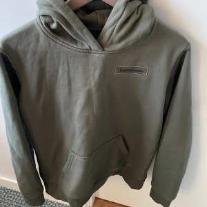 Grön hoodie från Peak Performance - Säljer en stilren grön hoodie från Peak Performance. Den har en klassisk design med en stor ficka framtill och en bekväm huva. Perfekt för en avslappnad look. Passar både för vardag och fritid.
