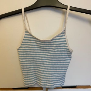 Blå- och vitrandig linnetopp från FB Sister - Säljer en söt blå- och vitrandig linnetopp från FB Sister. Toppen har smala axelband och är ribbad för en skön passform. Perfekt för varma sommardagar! 💙