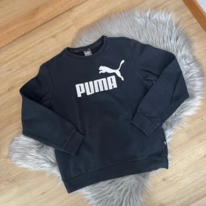 Svart sweatshirt från Puma - Säljer en svart sweatshirt från Puma med deras ikoniska logga i vitt på bröstet. Tröjan har långa ärmar och en klassisk rund halsringning. Perfekt för en avslappnad stil.