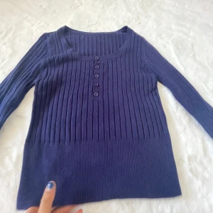 Mörkblå ribbad tröja - Säljer en stilren mörkblå ribbad tröja med knappar framtill. Tröjan har långa ärmar och en rund halsringning. Perfekt för en avslappnad look.aldrig använd! Skönt matrial!💙