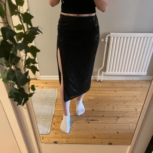 Svart paljett kjol med slits från NELLY - Snygg svart paljett kjol med en hög slits på sidan. 