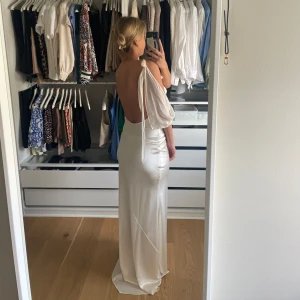 Champagnefärgad långklänning med öppen rygg - Elegant champagnefärgad långklänning i satin med smala axelband och en vacker drapering framtill. Klänningen har en stilren öppen rygg och en dekorativ knutdetalj vid axeln. Skriv privat för fler bilder!💕