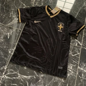 Svart Brasilien fotbollströja - Snygg svart Brasilien fotbollströja från Nike med guldiga detaljer. 