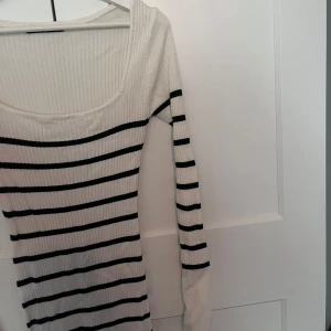 Randig ribbad klänning från Gina Tricot - Säljer en stilren vit och svart randig klänning från Gina Tricot. Klänningen är ribbad och har långa ärmar, perfekt för en chic look. Den är i storlek XS och passar utmärkt för både vardag och speciella tillfällen.
