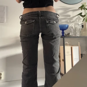 Gråa jeans med låg midja - Snygga gråa jeans med låg midja och två knappar fram. De har en klassisk femficksdesign och en rak passform som ger en avslappnad look.