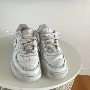 Vita Nike Air Force sneakers - Säljer ett par klassiska vita Nike Air Force sneakers. De har en rund tå och snörning framtill. Perfekta för en stilren look.