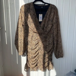 Leopardmönstrad klänning från Bik Bok - Snygg leopardmönstrad klänning från Bik Bok i storlek M. Klänningen har en omlott-design med v-ringning och långa ärmar. Den är dekorerad med volanger och har en åtsittande passform som framhäver figuren. Helt ny med prislapp kvar. Kostade från början 399. Hör av er vid frågor!💕