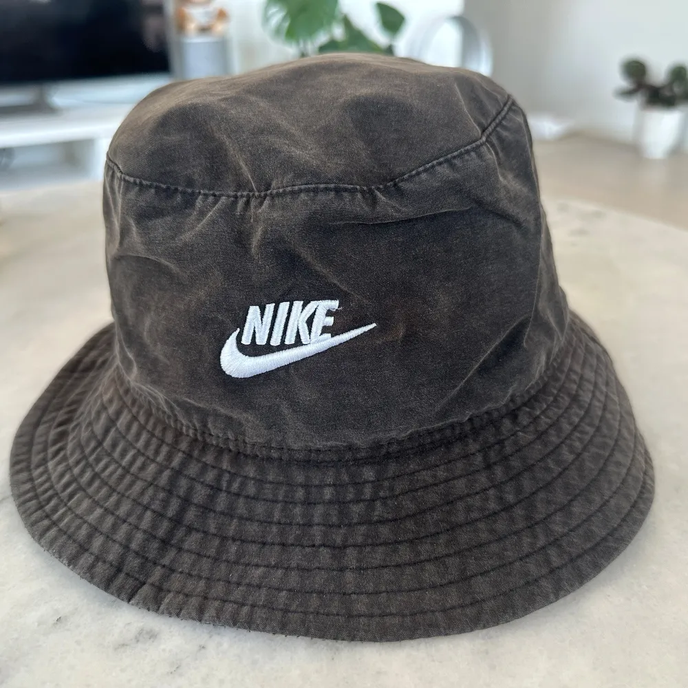 Snygg bucket hat från Nike med broderad logga framtill. Perfekt för en avslappnad stil. Hatten har en klassisk design med bred brätte och är tillverkad i ett slitstarkt material. . Asusteet.