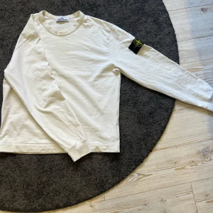 Vit Stone Island crewneck - Säljer en vit crewneck från Stone Island. Tröja är självklart äkta. Storleken är M men den har sytts upp vid mid midjan för att göra den lite kortare. Detta då den va för lång för mig. Annars är tröjan i nyskick och använd sparsamt. Tröjan har en klassisk design med ribbade muddar och det ikoniska Stone Island-märket på ärmen. Ordinarie pris: 2700kr mitt pris: 500kr då den är uppsydd vid midjan för att göra den lite kortare. Skickas samma dag!