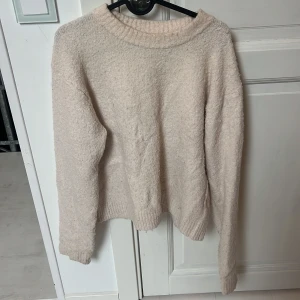 Ljusrosa fluffig stickad tröja H&M - Supermjuk och fluffig beige stickad tröja från H&M. Tröjan har en rund halsringning, ribbade muddar och lång ärm. Perfekt för lager-på-lager och chill dagar. Enkel att matcha med jeans eller kjol för en avslappnad look.