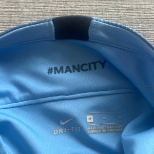 Manchester City Nike matchtröja M - Manchester Citys officiella matchtröja från Nike i ljusblått med mörkare blå detaljer på ärmarna. Tröjan har klubbmärke, Nike-logga och Etihad Airways-tryck på bröstet samt Nexen Tire på ärmen. Tillverkad i Dri-FIT-material för bästa komfort.