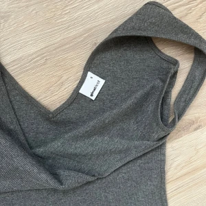 Grå ribbad långklänning Gina Tricot - Snygg grå långklänning från Gina Tricot i ribbad bomullsmix. Ärmlös modell med v-halsringning och figurnära passform. Perfekt för dig som gillar en enkel men stilren look.