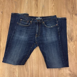 Mörkblå jeans från Grant modell 405 - Snygga mörkblå jeans från Grant, modell 405, med klassisk femficksdesign och kontrastsömmar. Jeansen har en rak passform och är tillverkade i slitstarkt denimtyg. Perfekta för en avslappnad och stilren look.