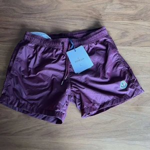 Vinröda badshorts från Moncler - Snygga vinröda badshorts från Moncler ä. Storlek L men sitter smått passar M