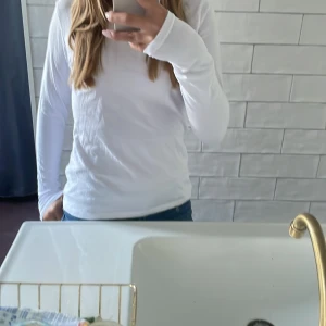 Vit långärmad tröja från Cubus - En basic vit långärmad tröja från Cubus i mjuk bomull. Tröjan har rund halsringning och en figurnära passform som funkar till allt. Perfekt att styla med jeans eller under en jacka. Enkel och clean look för dig som gillar minimalistiskt.