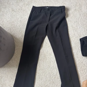 Svarta kostymbyxor från BikBok - Svarta kostymbyxor från BikBok i bootcut! Byxorna har midjehällor, diskreta fickor och stängs med dragkedja och hake. Perfekta för en clean och stilren look. Materialet känns mjukt och följsamt.