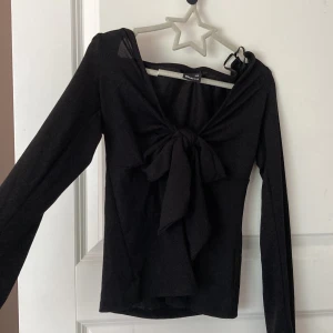 knyt top Gina Tricot - Supersnygg svart långärmad topp från Gina Tricot i storlek XXS. Toppen har en v-ringning och en stor knytrosett framtill som ger en trendig look. Perfekt att styla med jeans eller kjol för en cool outfit. Använd ca 5 gånger