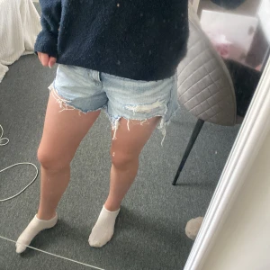Ljusa jeansshorts från American Eagle - Säljer ett par ljusblå jeansshorts från American Eagle med råa, fransiga kanter och slitna detaljer. Shortsen är lite högmidjade men syns ingenting om man har en tröja ovanför. Shortsen har använts ett antal par gånger. Står ej vad det är för storlek men passar på mig som har storlek Xs/S. 