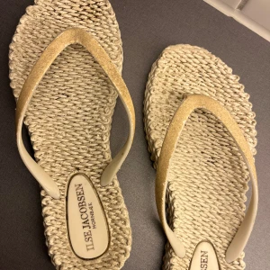 Beige flipflops från Ilse Jacobsen - Snygga beige flipflops från Ilse Jacobsen med glittriga remmar i guld. I fint skick! 