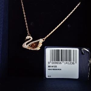 Swarovski halsband svan guld/röd - Supersnyggt halsband från Swarovski med en elegant svanformad berlock. Helt nytt, fått det som present. Jag vill sälja så fort som möjligt så lägg gärna bud om du är intresserad