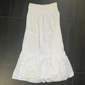 Vit långkjol från Gina Tricot - Superfin vit långkjol från Gina Tricot med broderade blommor och smock i midjan. Storlek 170 men skulle säga att den passar XXS, XS o S också.