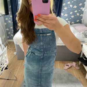 Jeans klänning  - Fin medellång jeansklänning med hängslen som går att justera. Jag har använt den nån enstaka gång så den är i mycket bra skick. Märke är hm x Lee och storleken är barn 152. Men den passar fortfarande på mig som har oftast har xs,s.