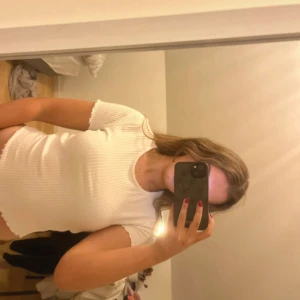 Vit ribbad topp med vågig kant - Supersöt vit ribbad topp med korta ärmar och vågiga kanter vid ärmslut och nederkant. Sitter tajt och har en enkel, clean look som passar till allt. Perfekt att styla med jeans eller kjol för en fräsch vibe. Oanvänd 