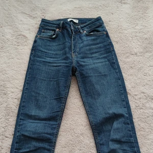 Blå bootcut jeans från Perfect Jeans - Snygga blå bootcut jeans från Perfect Jeans med klassisk femficksdesign och hög midja. Jeansen har en mörkblå tvätt och är tillverkade i mjukt denimtyg. Perfekta för dig som gillar en retroinspirerad look med utsvängda ben.