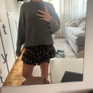 Blommig volangkjol i marinblått - Supersöt kort volangkjol med blommigt mönster i marinblått, rosa, beige och vitt. Kjolen har resår i midjan och flera lager volanger som är jättefint. Perfekt för dig som gillar en feminin och lekfull stil. Skulle själv säga att den är större än 158, mer som en S. 